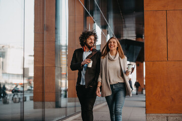 Business man and business woman talking and holding luggage traveling on a business trip, carrying fresh coffee in their hands.Business concept