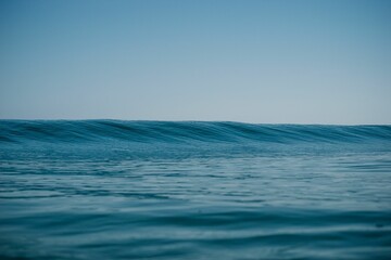 Obraz premium Gorgeous view of a bright blue sea with calm tides rising slowly rising under a clear sky