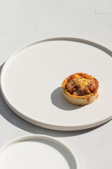 Photo of a delicious modern style handmade mini tart tartlet fulled with differ nuts like pistachio and hazelnut with salted caramel sause on a modern porcelain white flat plate on white background
