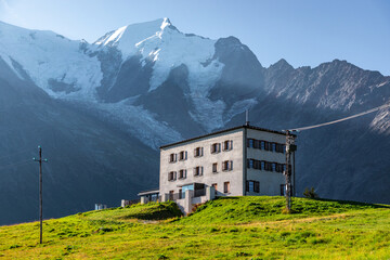 Hotel in Mont-Blanc massif. This hotel is located near Chamonix, in the french Alps. In the back, Aiguille de Bionnassay and the Bionnassay Glacier can be seen. - obrazy, fototapety, plakaty