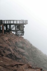 Edge of metal bridge over stones of pikes peak in Colorado under a foggy gray sky, vertical shot