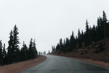 Highway asphalt road under pikes peak mountains with trees in Colorado