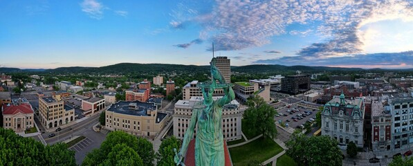 Panoramic aerial shot of the cityscape of downtown Binghamton, with a green statue in the middle