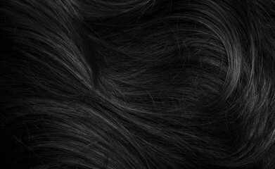 Naklejka premium Brunette or black hair. Female long dark hair in black. Beautifully laid curls. Closeup texture in a dark key. Hairdressing, hair care and coloring. Shading gray hair. Background with copy space.