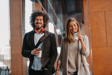 Business man and business woman talking and holding luggage traveling on a business trip, carrying fresh coffee in their hands.Business concept