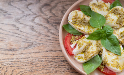 delicious italian caprese dish with mozzarella tomatoes and pesto sauce with copy space on a wooden background