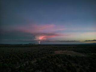 Scenic shot of a plain field with a lightning strike on the sky during dusk