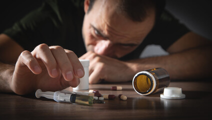 Drug addict man with a syringe and drugs. Addiction