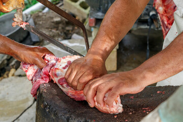 Men in the countryside cut up pieces of beef. Farmers prepare meat for sale.