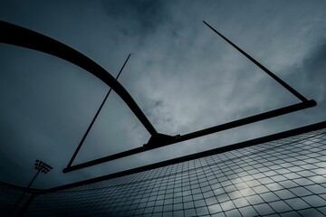 Closeup of a volleyball fence with a cloudy blue sky in the background