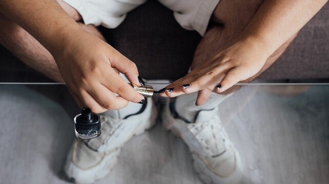 High Angle Shot Of A Man Putting Black Nail Polish On His Nails