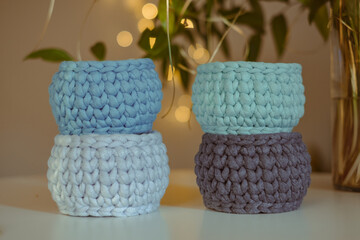 Obraz na płótnie Canvas Four blue decorative hand crocheted baskets, sustainable handicraft business, cozy Christmas atmosphere with decorative plants and blurred Christmas bouquet in the background