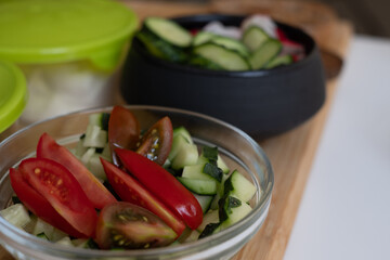 black and glass bowls with cucumbers, tomatoes, radishes and other vegetables, healthy cooking