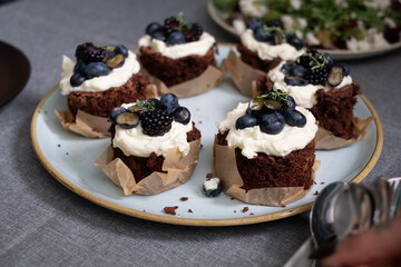 brownie muffins with cream and blueberries on a plate. A plate of healthy green salad on a blurred background