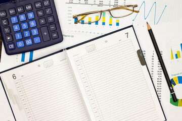 Top view office table desk. Financial report. Flat lay. Workspace with Business office supplies, numbers and empty sheet of diary, diagrams, pencil, glasses, calculator. Copy space for text. Top view