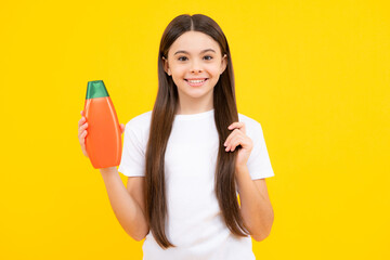 Teenager child girl showing bottle shampoo conditioners or shower gel. Hair cosmetic product. Bottle for advertising mock up copy space. Happy teenager portrait. Smiling girl.
