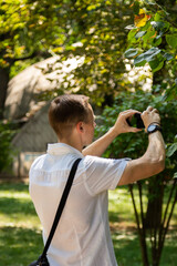 A young man walks and photographs nature