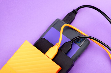 Multicolored external portable hard disk drives isolated on violet background