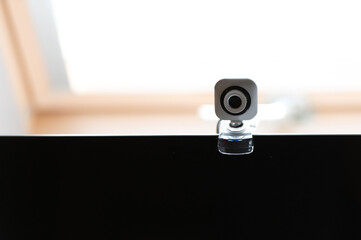Webcam above computer screen. White webcam above black screen. Digital security concept