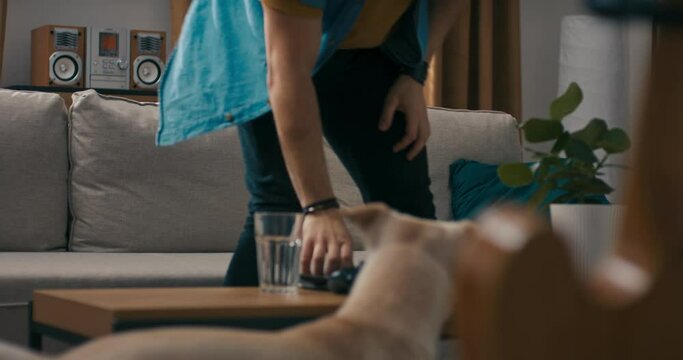 Man enters living room with four-legged shaggy friend. The bearded man with glasses browses the internet social media on phone, strokes his dog looks at the pet sitting next to him on the couch.