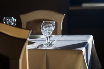 Sunlit empty glasses on the white tablecloth , selective focus