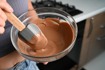 The process of tempering chocolate and making chocolates. Pastry chef using spatula tempering molten chocolate