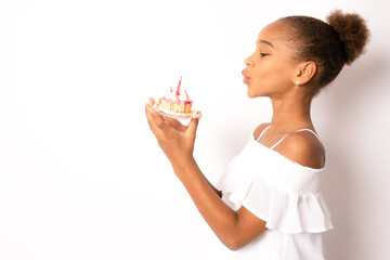 Cute adorable child african american girl celebrating birthday while holding strawberry cake and...
