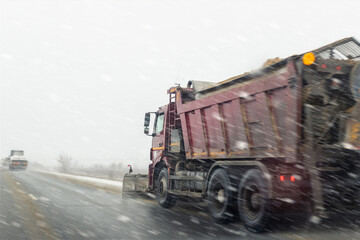 Snowplow truck removing dirty snow from city street or highway after heavy snowfalls. Traffic road...