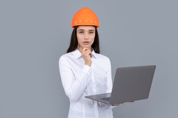 Young beautiful architect woman in hard hat helmet hold laptop computer over gray background. Female builder in helmet for advertising sign.