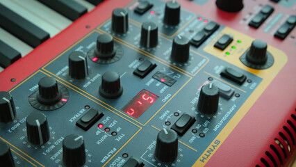 Close-up of professional synthesizer with control knobs and display.