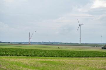 Green agricultural field with wind turbines under the cloudy sky