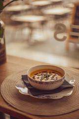 Pumpkin puree soup on a wooden background. Autumn cream soup decorated with pumpkin seeds and basil.