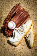 Baseball glove, baseball, and baseball cleats on a field in a park in Central Florida