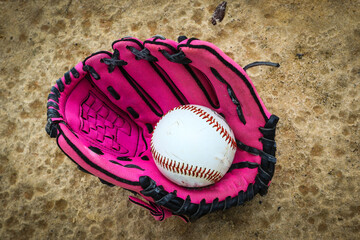 Close-up of Baseball Equipment including girls pink baseball glove and baseball at park in Central Florida