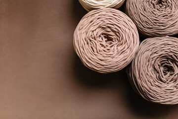 Beige and gray knitted threads on a brown background with space for text. Knitted yarn for knitting. A concept for creativity
