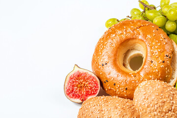 Bagel with sesame and soft buns with figs and grapes for breakfast. Natural products for cooking with a place for text.