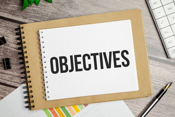 OBJECTIVES word on white notebook and charts, pen and calculator
