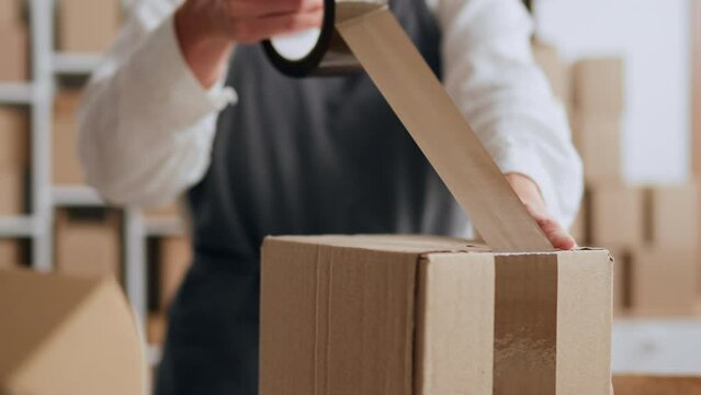 Small business owner business lady packs boxes by herself to send to buyers customers, Packing boxes taping the box close-up. Warehouse worker at the logistics center
