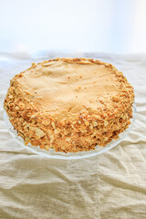 napoleon cake, round whole with caramel cream on a white background. copy space