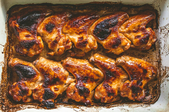 appetizing baked chicken wings in a baking sheet, top view