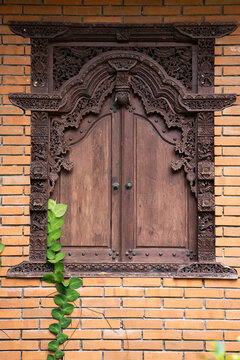 Javanese style wood carved window in brick wall