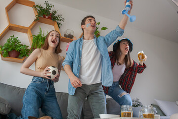 Three friends, celebrating and shouting that their soccer team scored a goal.