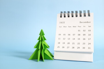 Selective focus of December 2022 desk calendar on blue background with christmas tree and copy...