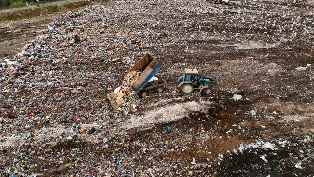 Garbage truck unloads rubbish, drone view.Landfill with solid household waste. Waste plastic and polyethylene on Garbage dump. Solid waste disposal on landfill, aerial view. Environmental pollution.
