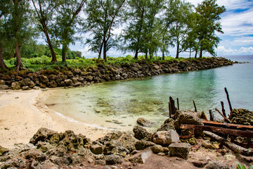 Tropical beach, rusty ruin, sand, trees and blue green ocean in Angaur island, Palau, Pacific