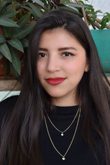 Retrato de una mujer Joven Hispana, con ojos bonitos y piel morena en un jardin al aire libre.