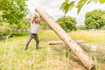 Strong woodcutter lifting a log with his bare hands
