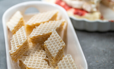 Home-made European style desserts with fresh raspberries on white ceramic serving trays against a dark grey background.