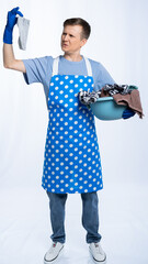 man in blue apron, rubber gloves, blue t-shirt, jeans. the homeowner holds a basin with dirty...