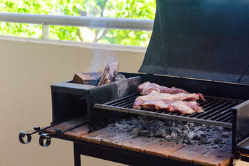 Making a barbecue with a portbale grill in the balcony of apartment. Traditional roast beef of...